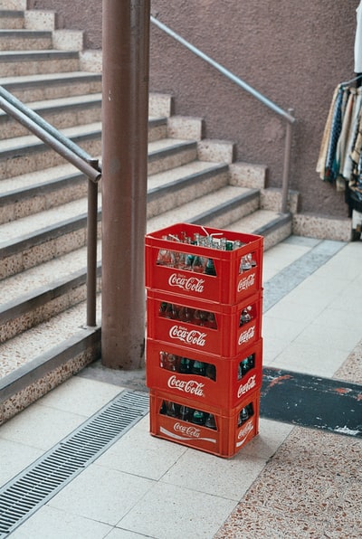 楼梯附近有一堆四个红色可口可乐瓶箱